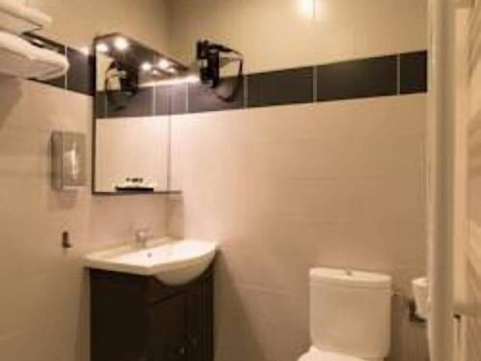 A bathroom with a white sink, dark cabinet, and a toilet.