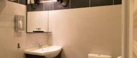 A bathroom with a white sink, dark cabinet, and a toilet.