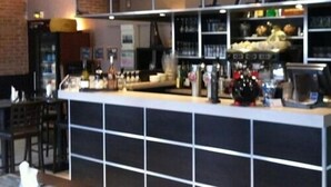 A bar area with a counter, shelves stocked with bottles, and a coffee machine. - Storia Da Ennio (La Verriere)