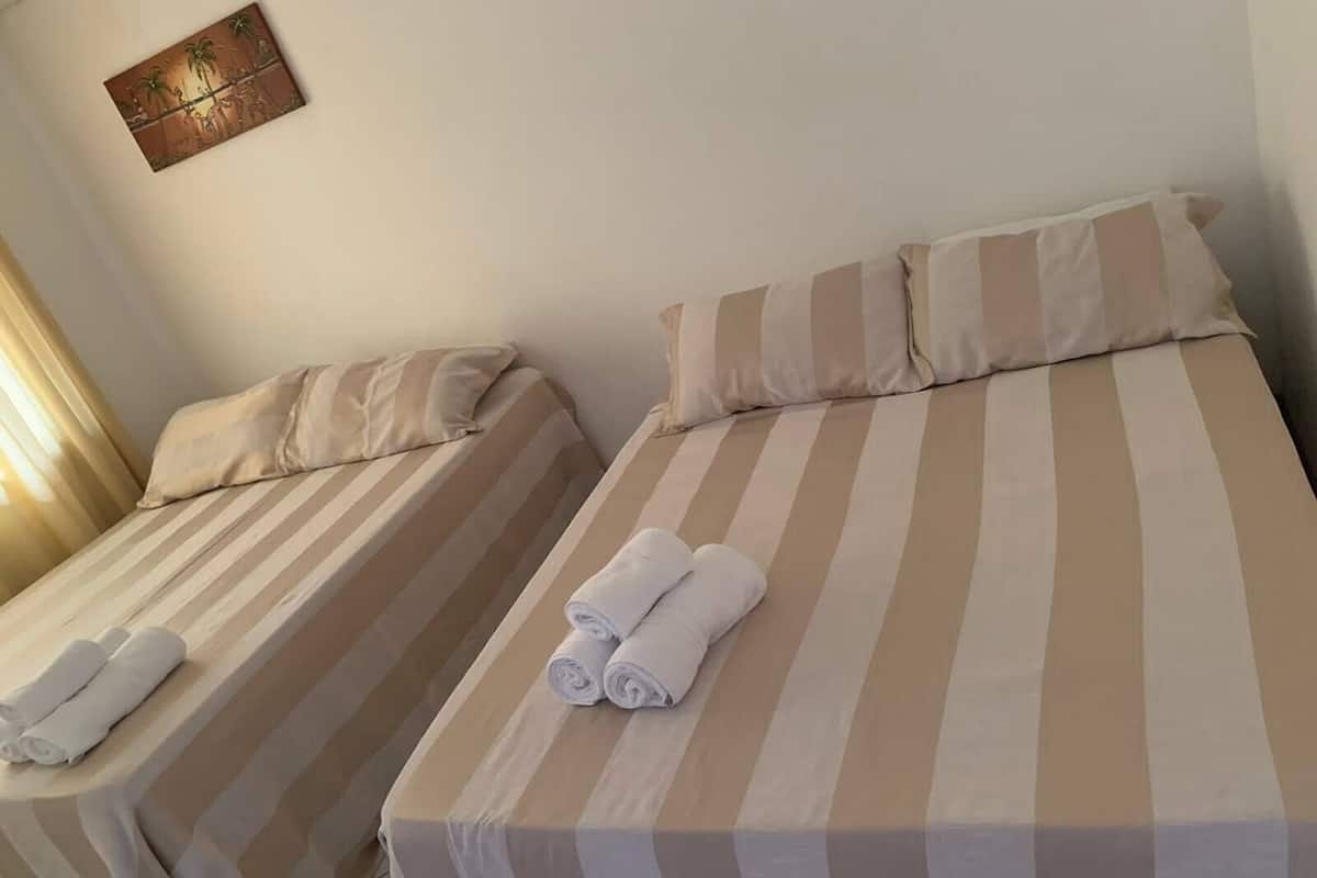 Two single beds with striped bedding, a wall clock, and a painting.