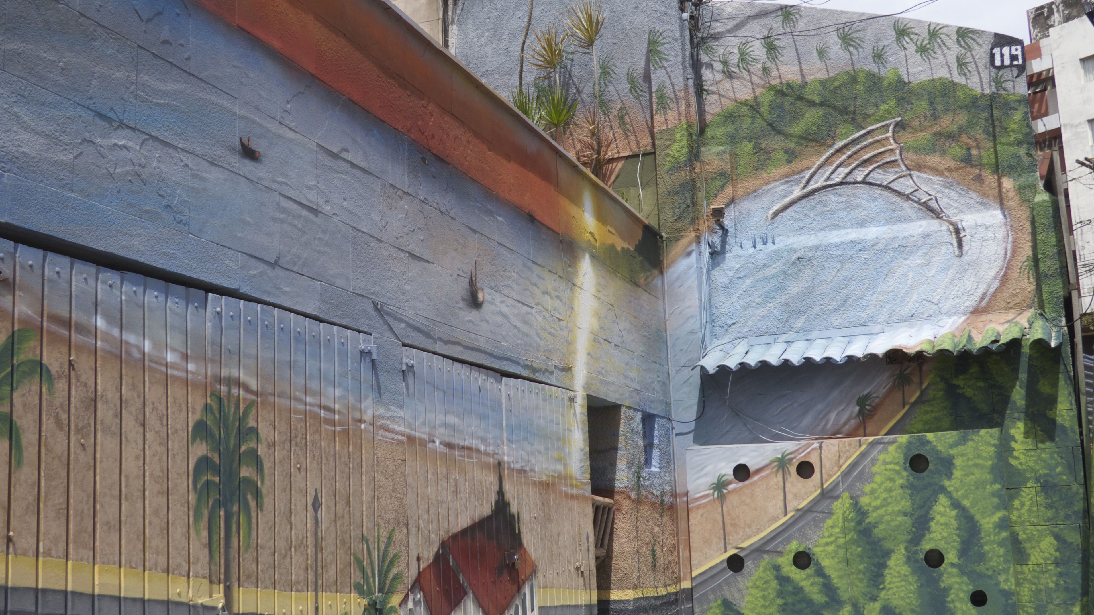 Um mural retratando uma cena de praia com palmeiras, uma escada e uma estrada.