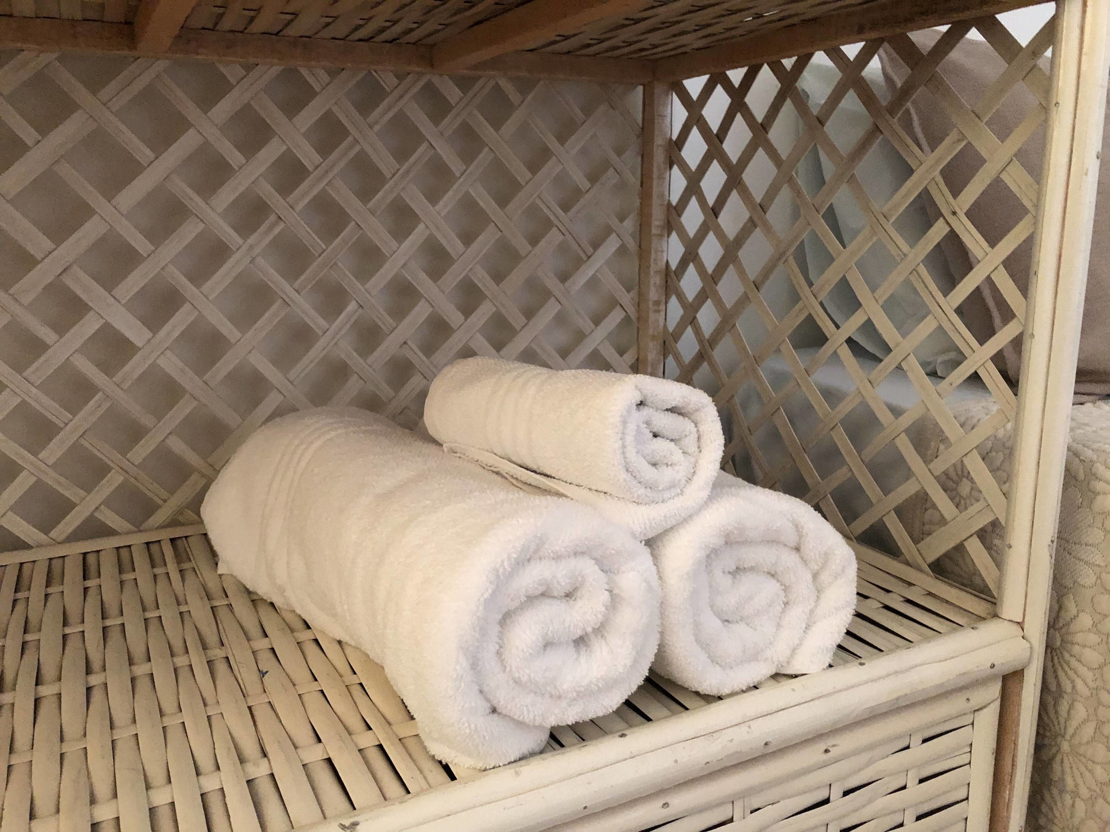 A wicker basket with two rolled white towels.