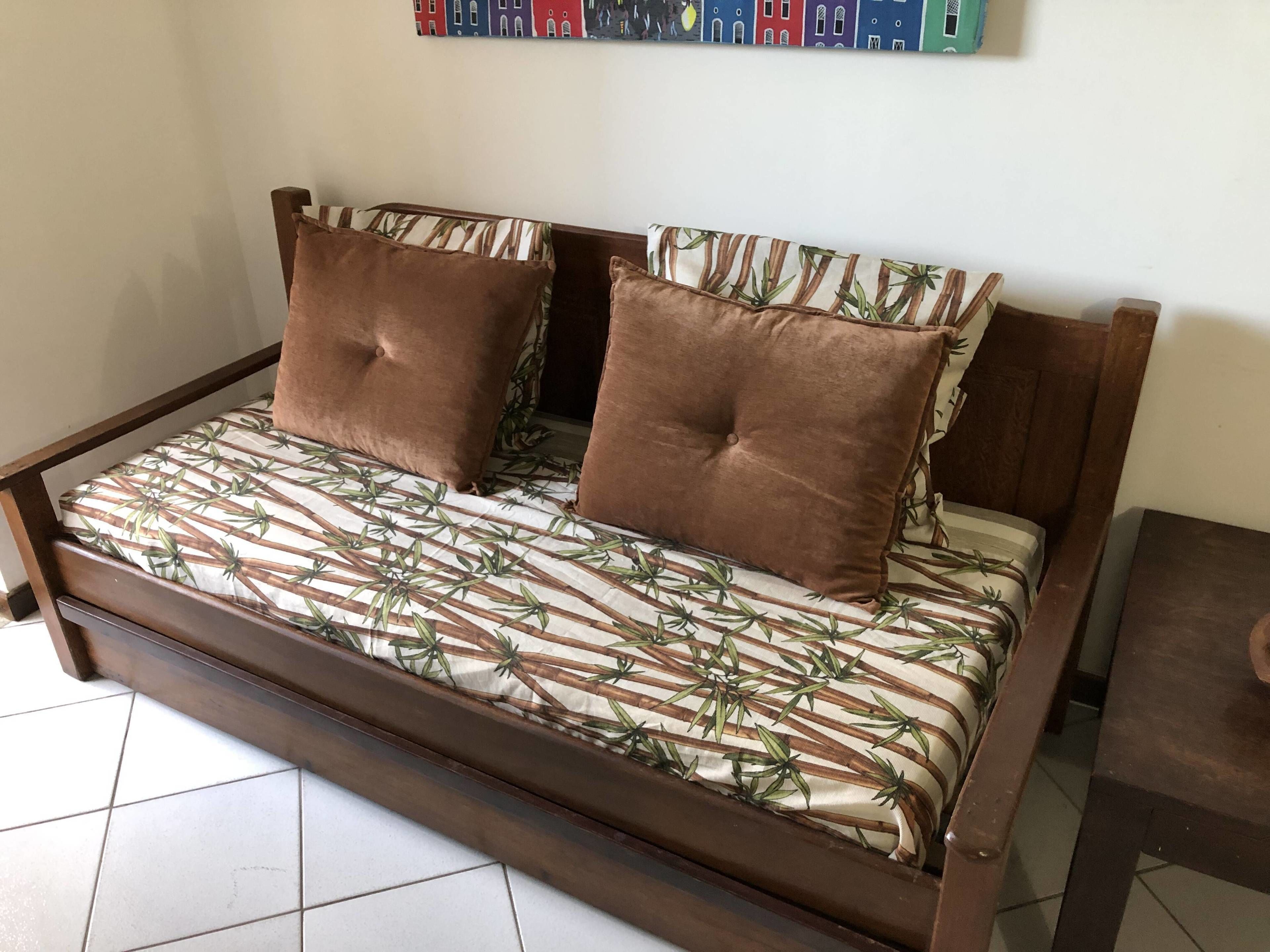 Puisesta rungosta valmistettu sohvasänky, jossa on bambunlehtikuviollinen päällinen ja kaksi ruskeaa koristetyynyä.