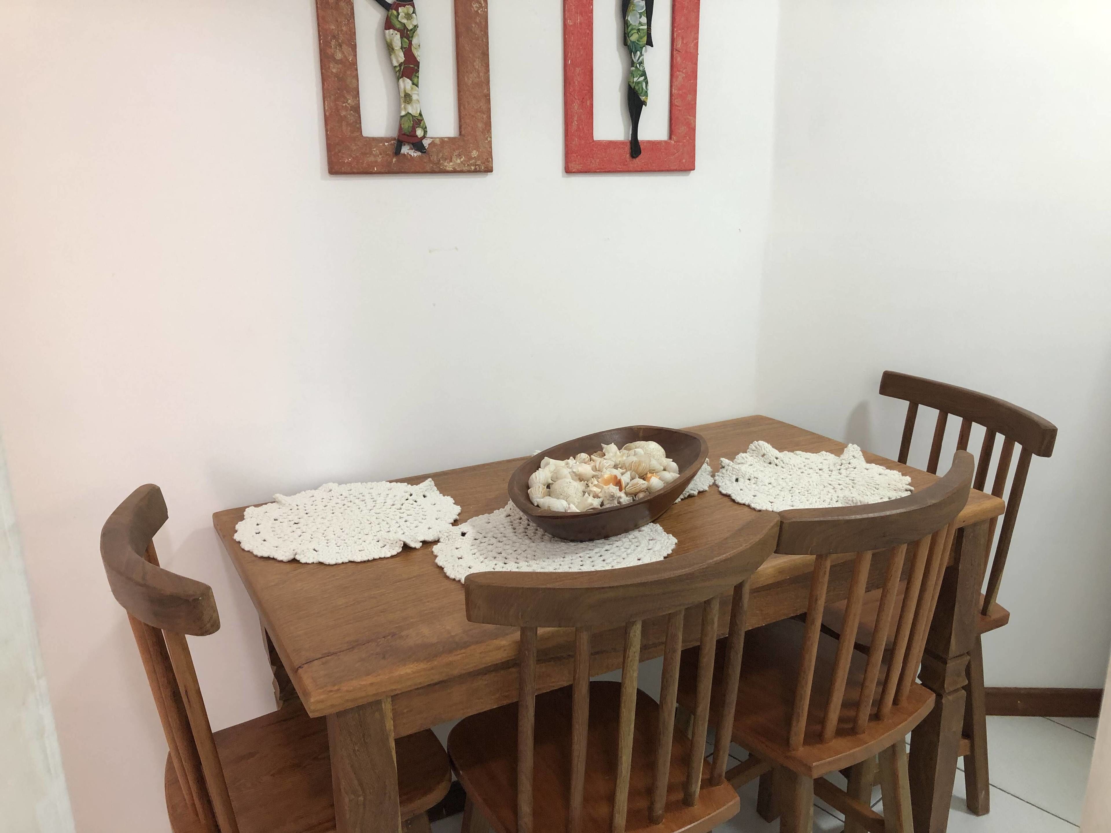 A wooden dining table with a bowl of snacks, two doilies, and a wooden chair.