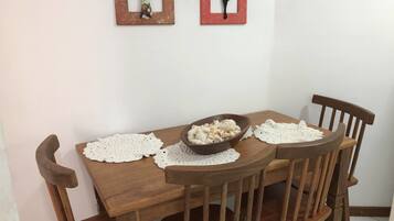 A wooden dining table with a bowl of snacks, two doilies, and a wooden chair.