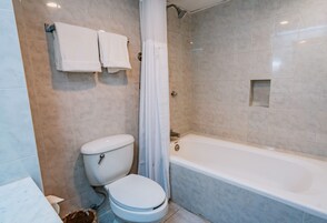 Un baño con inodoro, bañera y dos toallas colgadas en la pared.