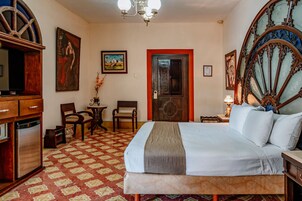 Une chambre d’hôtel avec un lit, un bureau, une chaise, une télévision et une porte.