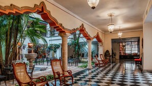 A spacious lobby with a checkered floor, wooden rocking chairs, and a fountain. - Casa del Balam Merida (Mérida)