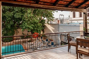 Ein Balkon mit Pool, Gartenmöbeln und Blick auf einen Baum und ein Gebäude.