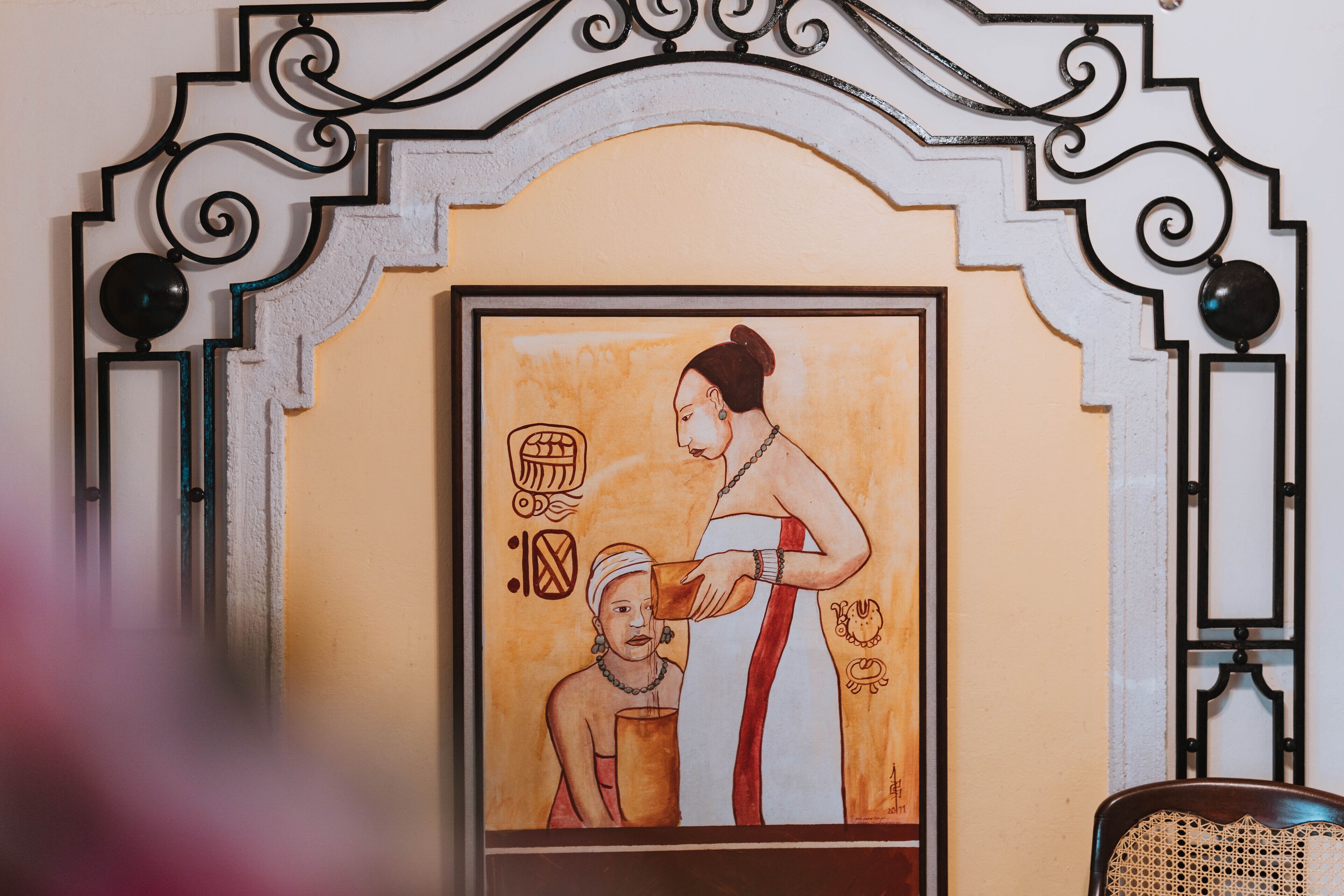 Una obra de arte enmarcada en una pared, con un marco metálico decorativo.