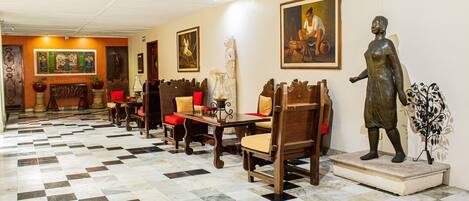 A lobby with a checkered floor, wooden furniture, and artwork on the walls.