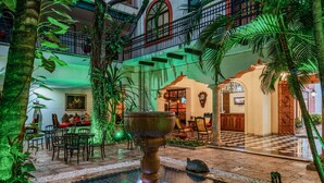 A courtyard with a central fountain, surrounded by greenery and a checkered floor. - Casa del Balam Merida (Mérida)