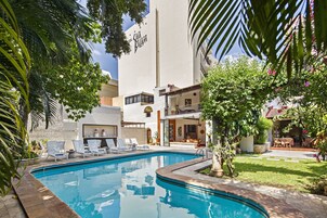 Ein Schwimmbecken mit Liegestühlen, ein Gartenbereich und ein Gebäude mit dem Schild "El Cabañal".