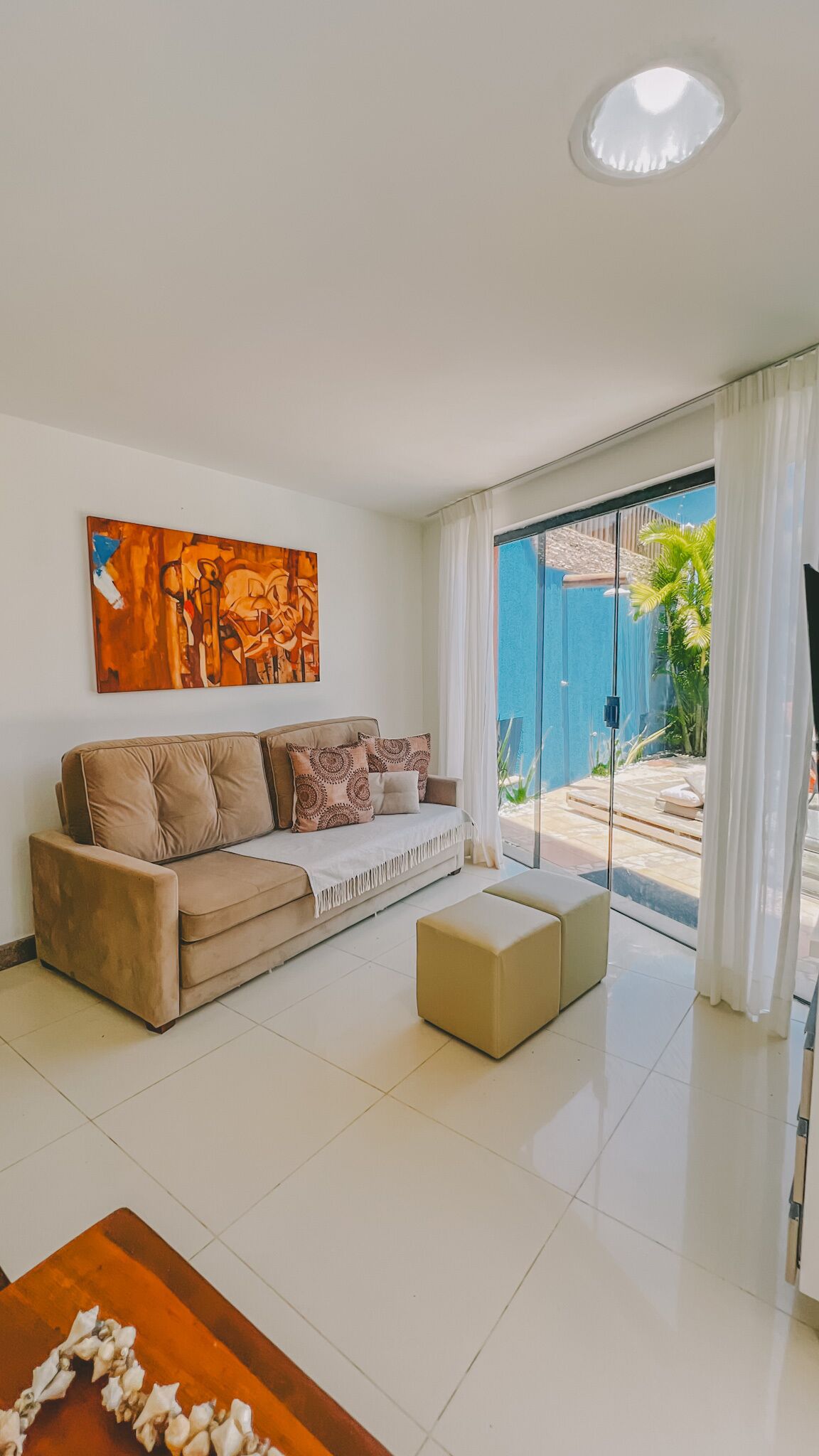 A modern living room with a beige sofa, a coffee table, and a painting on the wall.