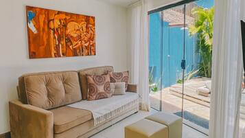A modern living room with a beige sofa, a coffee table, and a painting on the wall.
