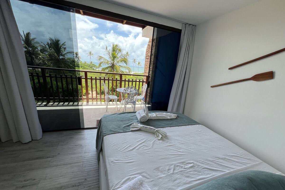 A hotel room with a bed, a view of palm trees and a balcony.