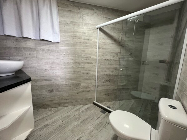 A modern bathroom with a shower enclosure, a toilet, and a sink.