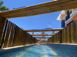 Uma piscina de madeira com superfície de água azul cristalina e um deck de madeira ao redor.
