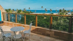 A terrace with a table and chairs, overlooking a beach and palm trees. - Villaggio Orizzonte (Salvador)