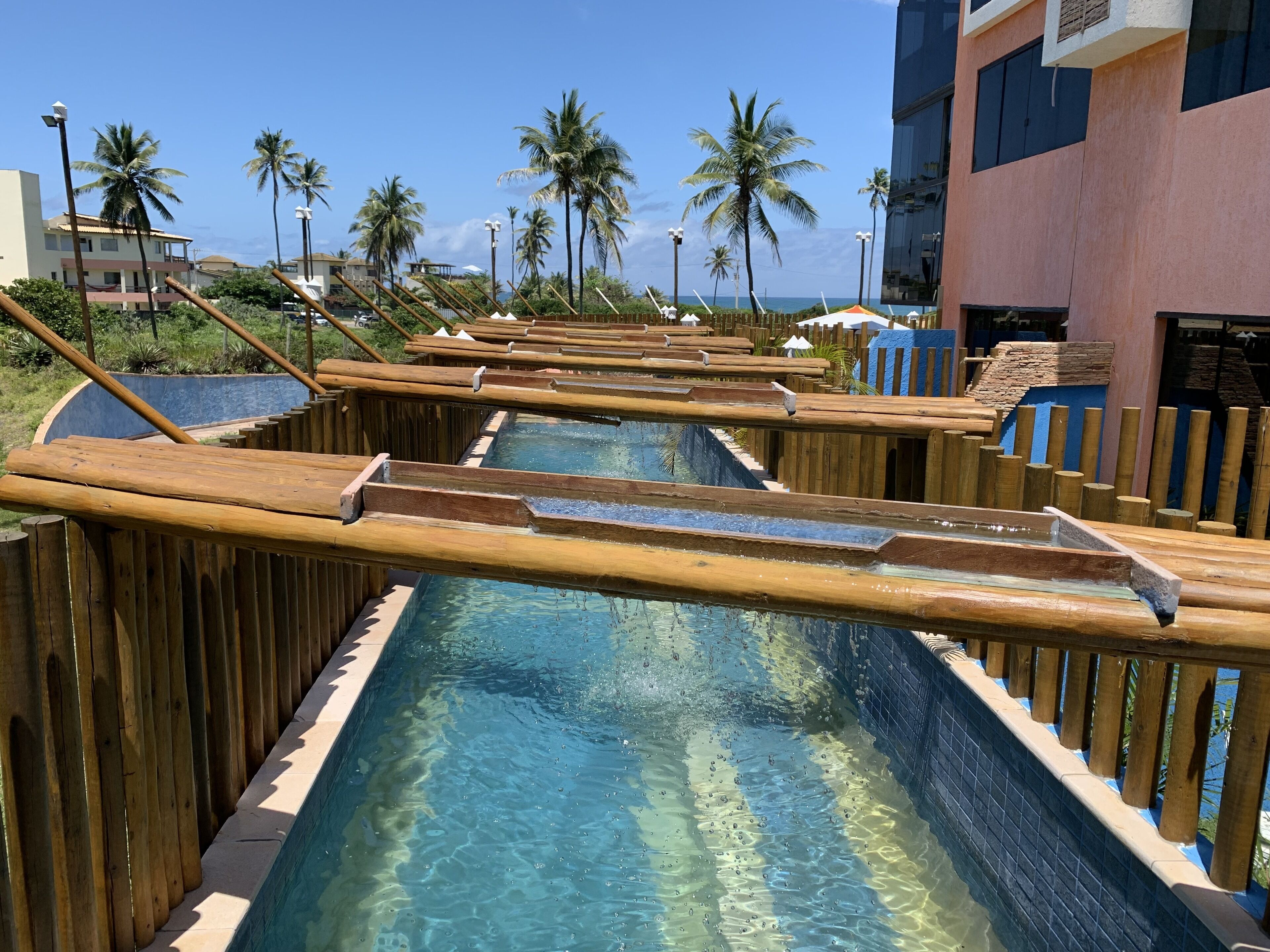 A pool area with wooden walkways and palm trees in the background.