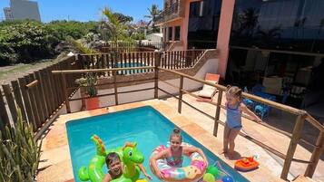 Piscina com brinquedos infláveis e uma criança perto da borda.