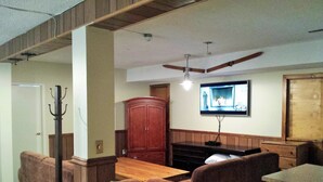 Ein Wohnzimmer mit Holztisch, zwei braunen Sofas, einer Holzkommode und einem Deckenventilator.