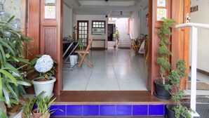 A hotel lobby with a tiled floor, wooden doors, and a staircase leading to the upper floor. There are potted plants and a reception desk visible. - Albergue Rio Vermelho - Hostel (Salvador)