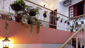 A multi-level building with balconies, potted plants, and a staircase. - Albergue Rio Vermelho - Hostel (Salvador)
