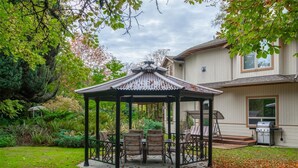A gazebo with a roof, surrounded by a lawn and trees. - Cedar Wood Lodge B&B (Port Alberni)
