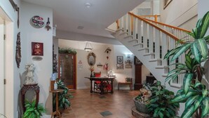 A spacious foyer with a staircase, a dining area, and various decorative items. - Cedar Wood Lodge B&B (Port Alberni)