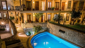 A multi-level hotel with a central swimming pool, stone walls, and balconies with plants. - Hotel Boutique Casa Mateo (Ezequiel Montes)