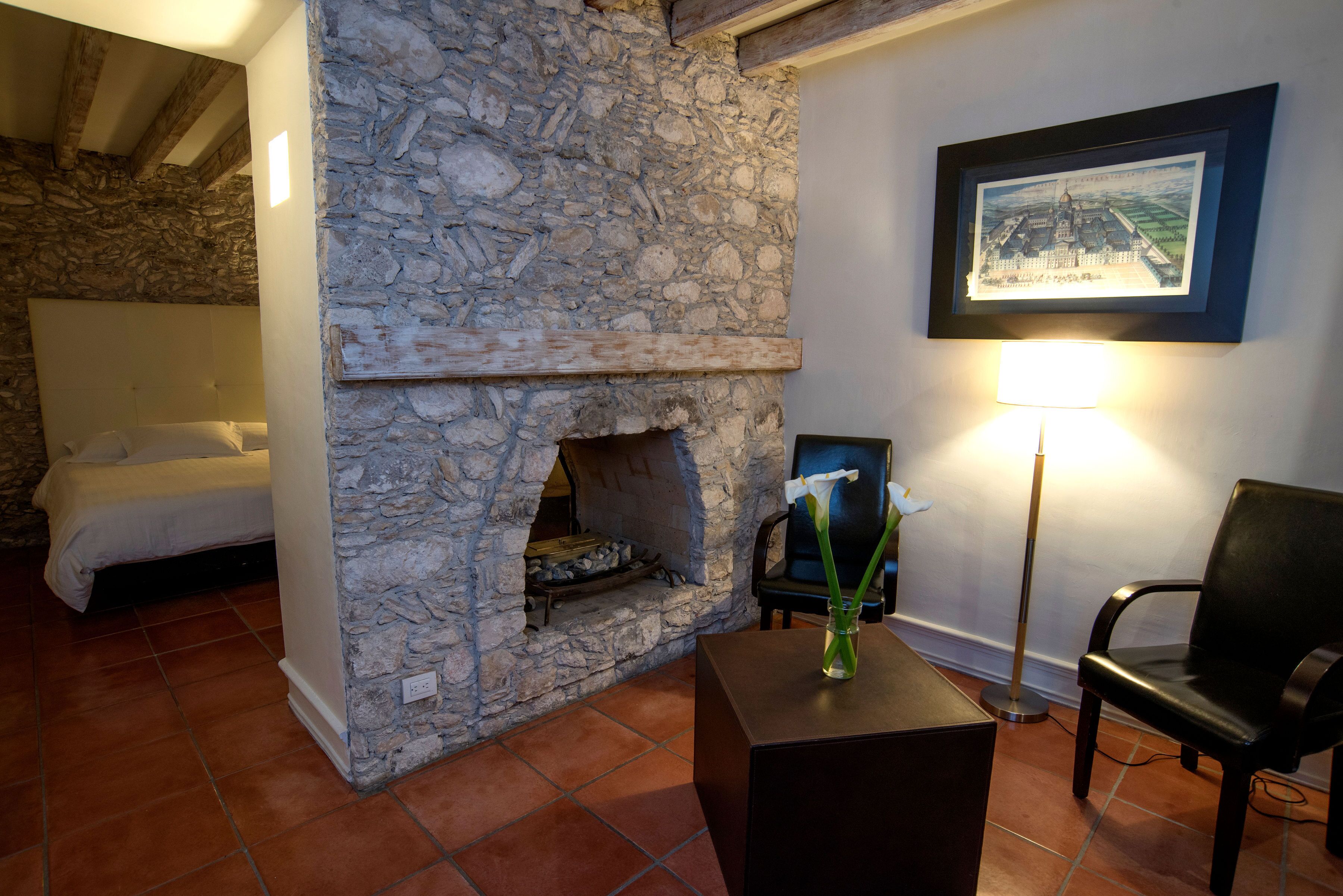 A stone fireplace, a bed, a chair, and a framed picture on the wall.
