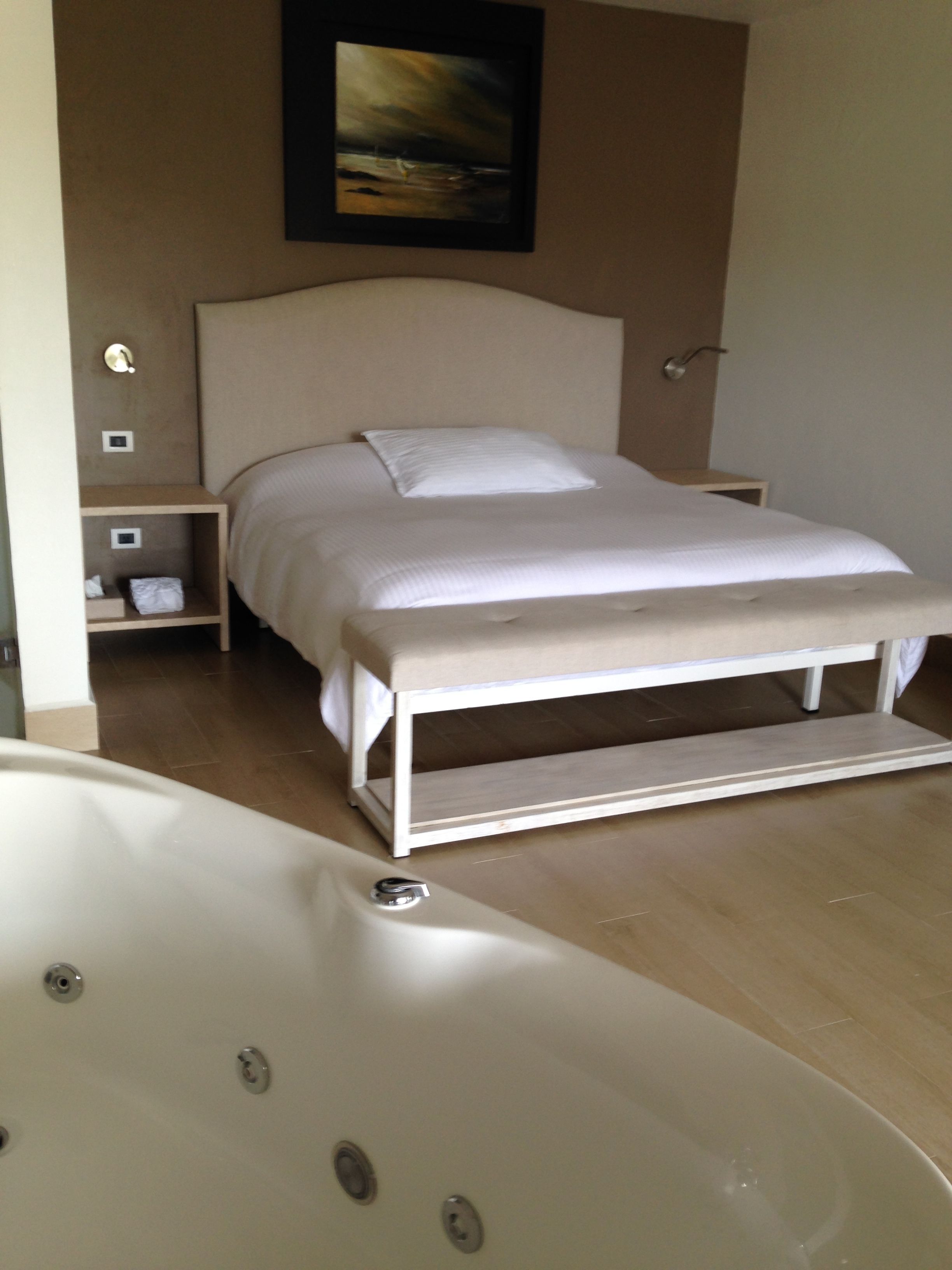 Ein Schlafzimmer mit einem Bett, einem Nachttisch, einer kleinen Ablage und einer Badewanne.
