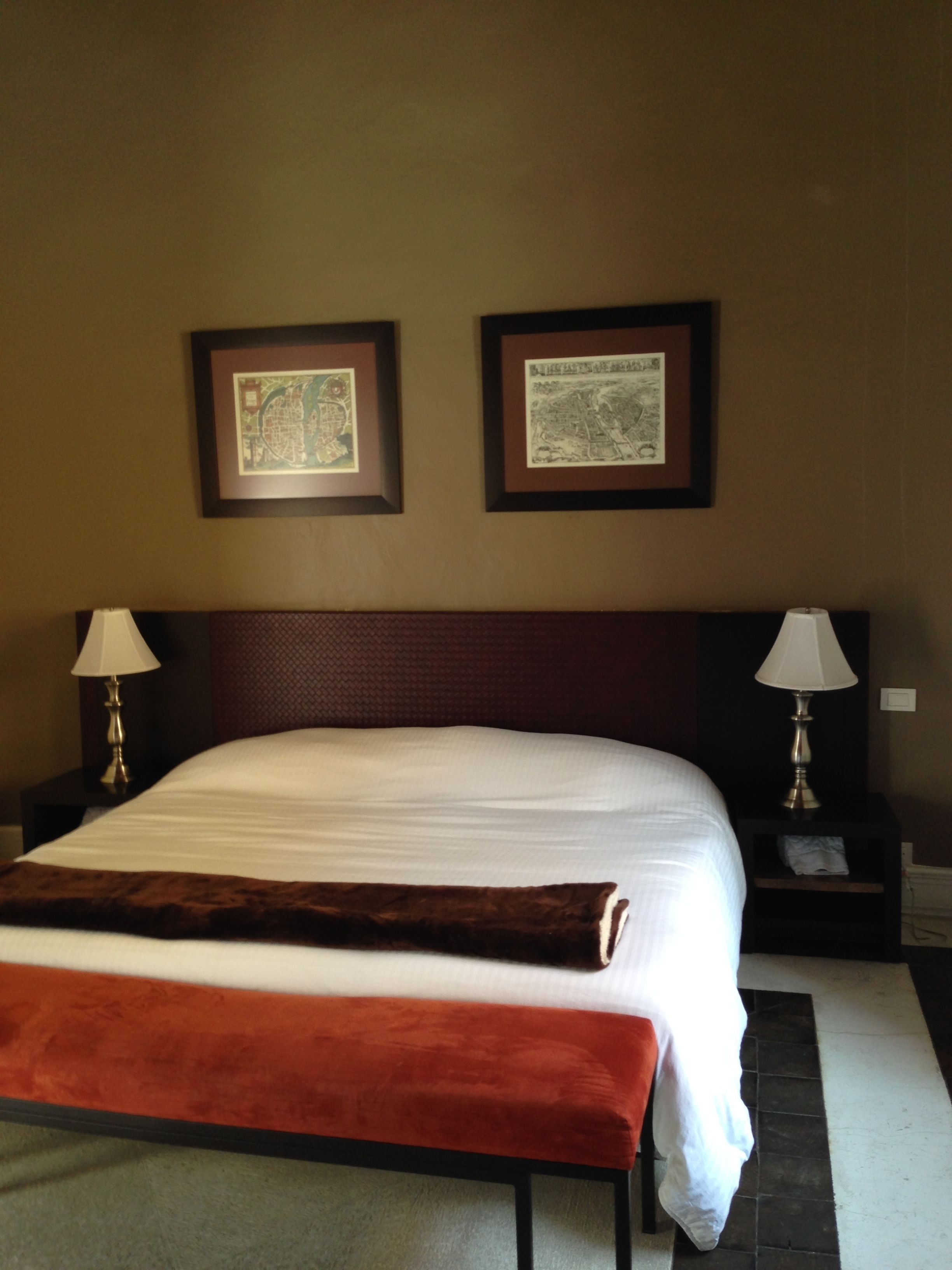 A hotel room with a large bed, two bedside tables with lamps, and two framed pictures on the wall.