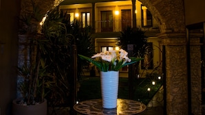 An arched entrance with a stone wall, a hanging light fixture, a potted plant, and a table with a vase of flowers. - Hotel Boutique Casa Mateo (Ezequiel Montes)