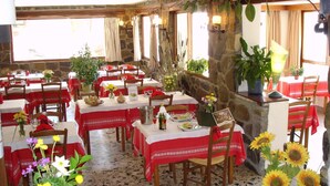 A restaurant with stone walls, red tablecloths, and sunflowers. Tables are set with wine glasses and plates. - Hôtel Le Parpaillon (Crevoux)