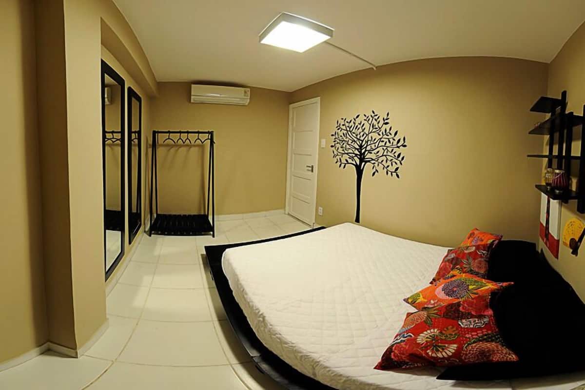 Quarto com cama, espelho, guarda-roupa, porta e decoração na parede.
