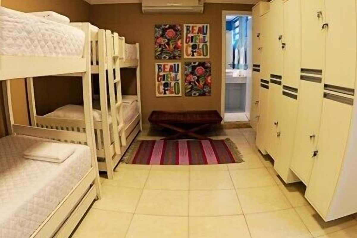 Um dormitório com beliches, piso de azulejos, tapete colorido e armários.