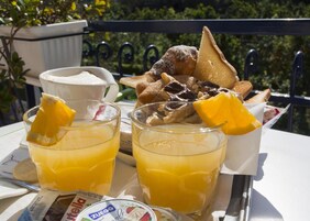 A breakfast setting with two glasses of orange juice, a cup of coffee, and a variety of pastries on a table.
