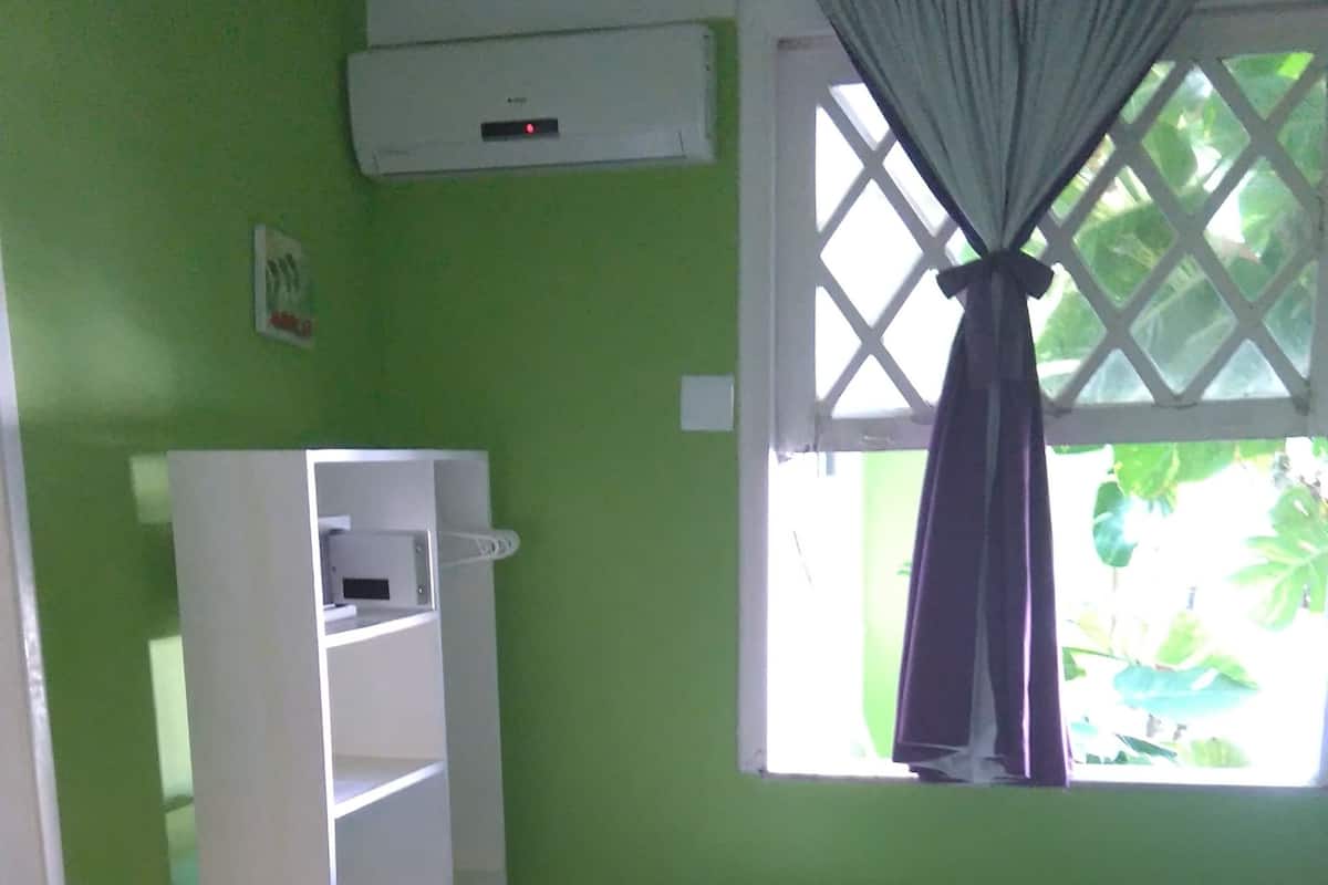 Ein Schlafzimmer mit einem Bett, einem weißen Kleiderschrank, einem Fenster mit Vorhängen und einer grünen Wand.