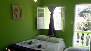 Een kamer met twee bedden, een plafondventilator, een raam met gordijnen en een inlijsting foto aan de muur.
