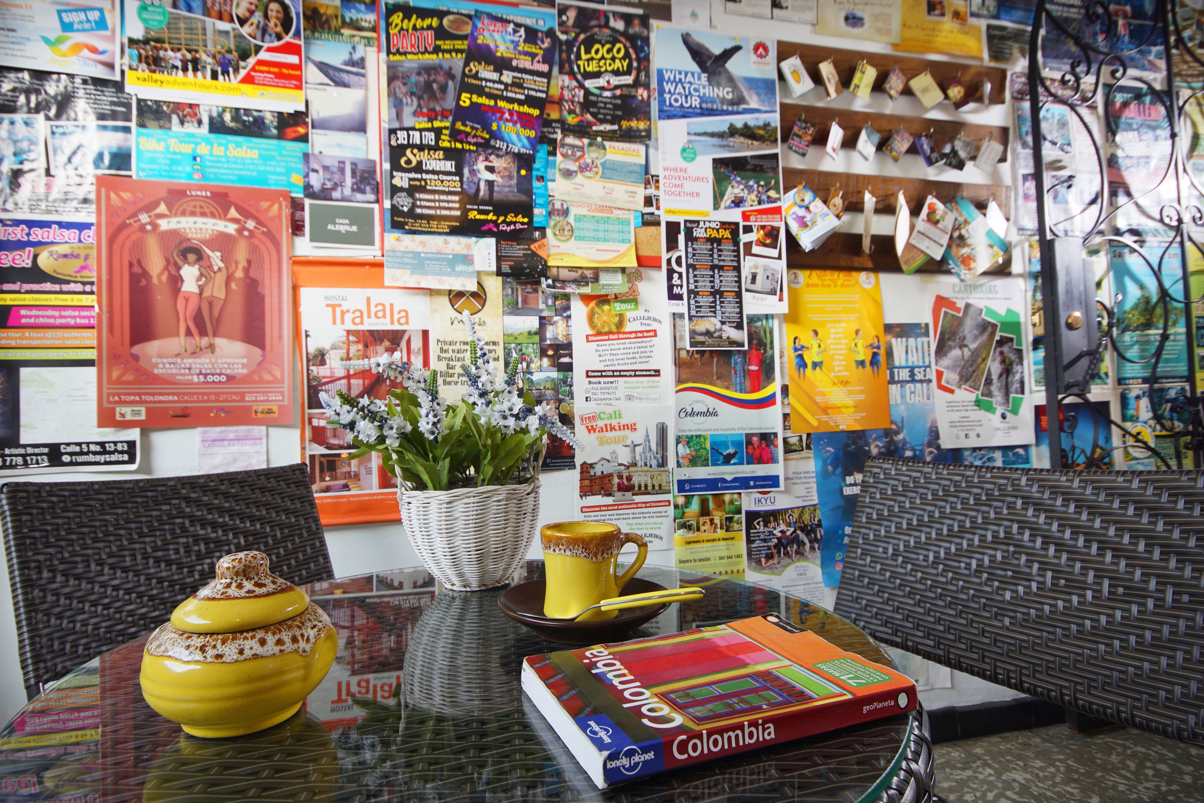 A table with a book titled 'Colombia', a yellow pot, a mug, and a basket with flowers.