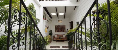 Una escalera conduce a una sala de estar con un sofá, plantas y una lámpara colgante.
