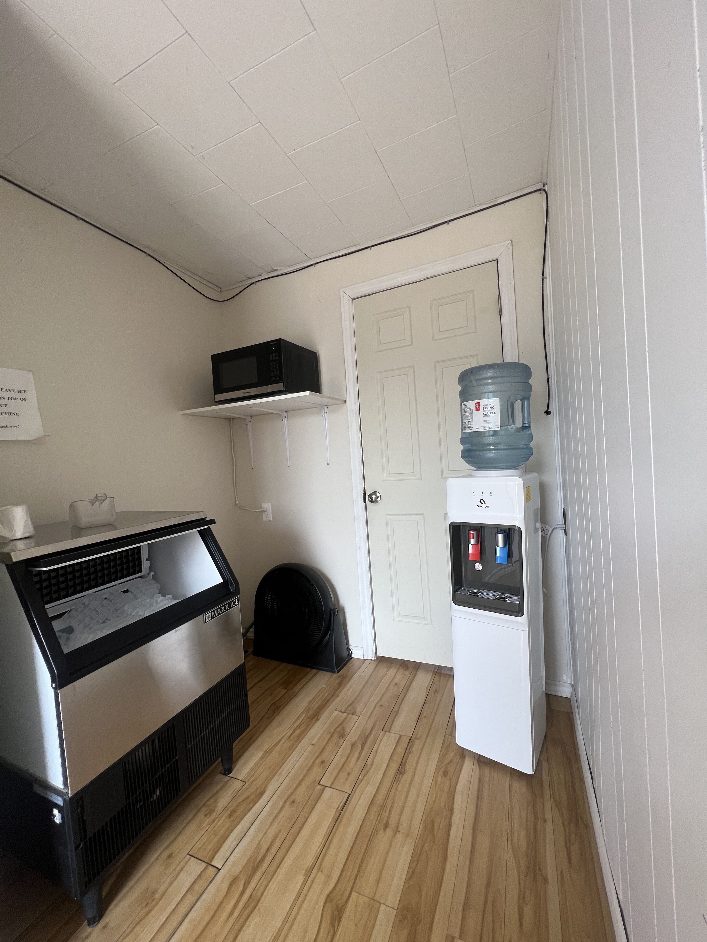 A small kitchenette with a microwave, a water dispenser, and a fan.