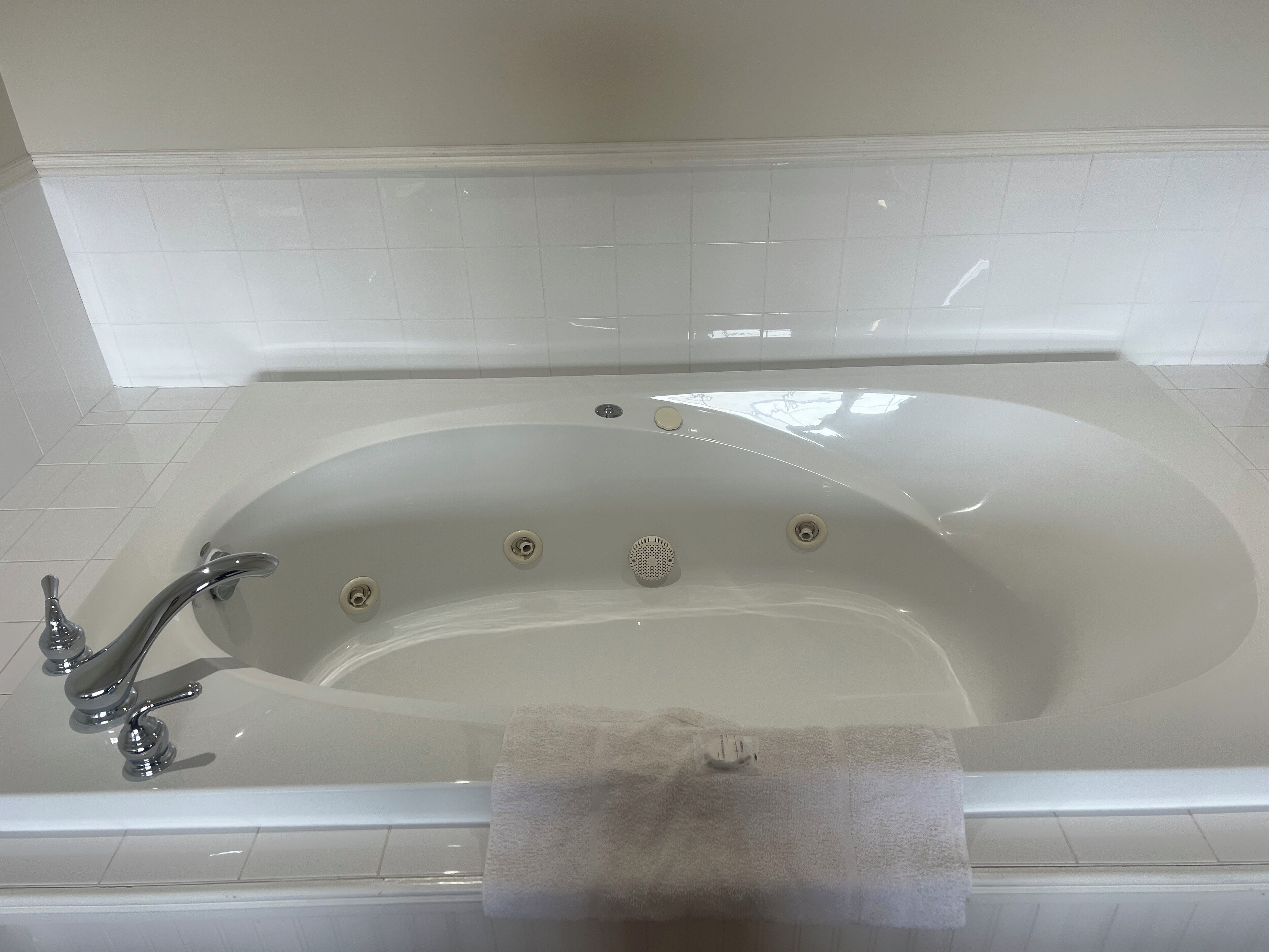 A white bathtub with a single faucet and multiple drain holes.