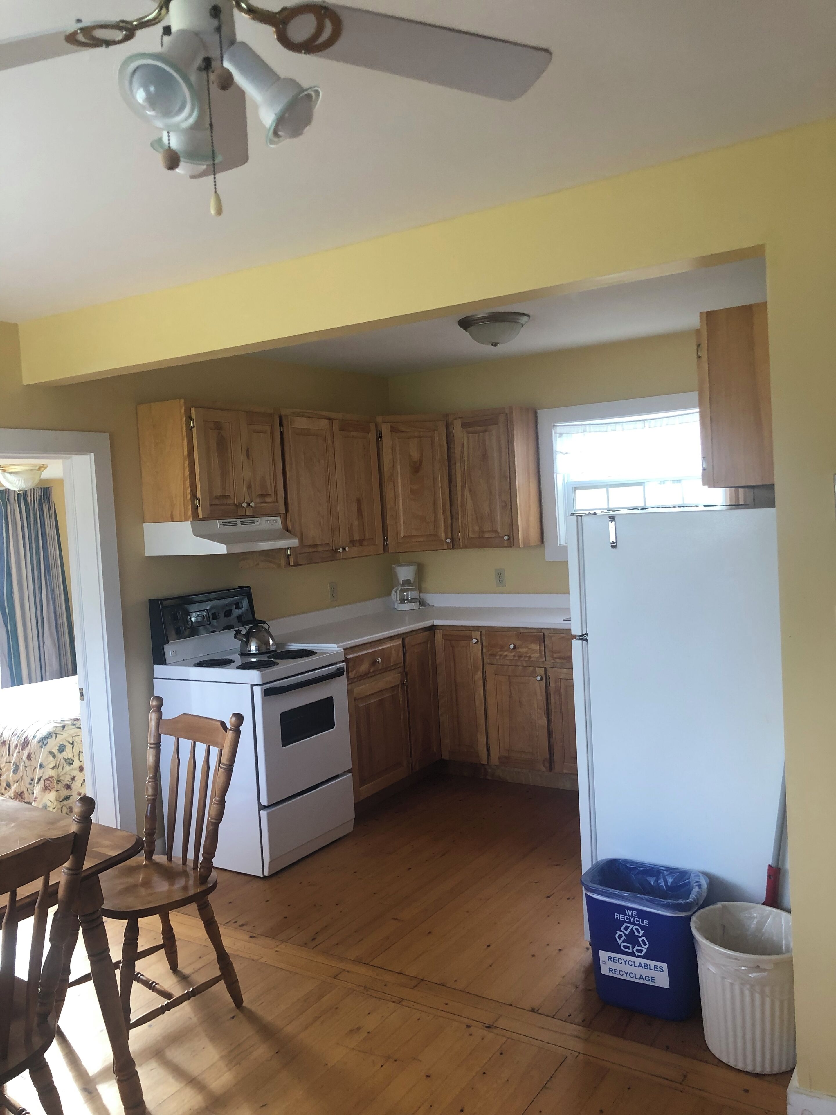 A kitchen with wooden cabinets, a stove, a refrigerator, and a ceiling fan.