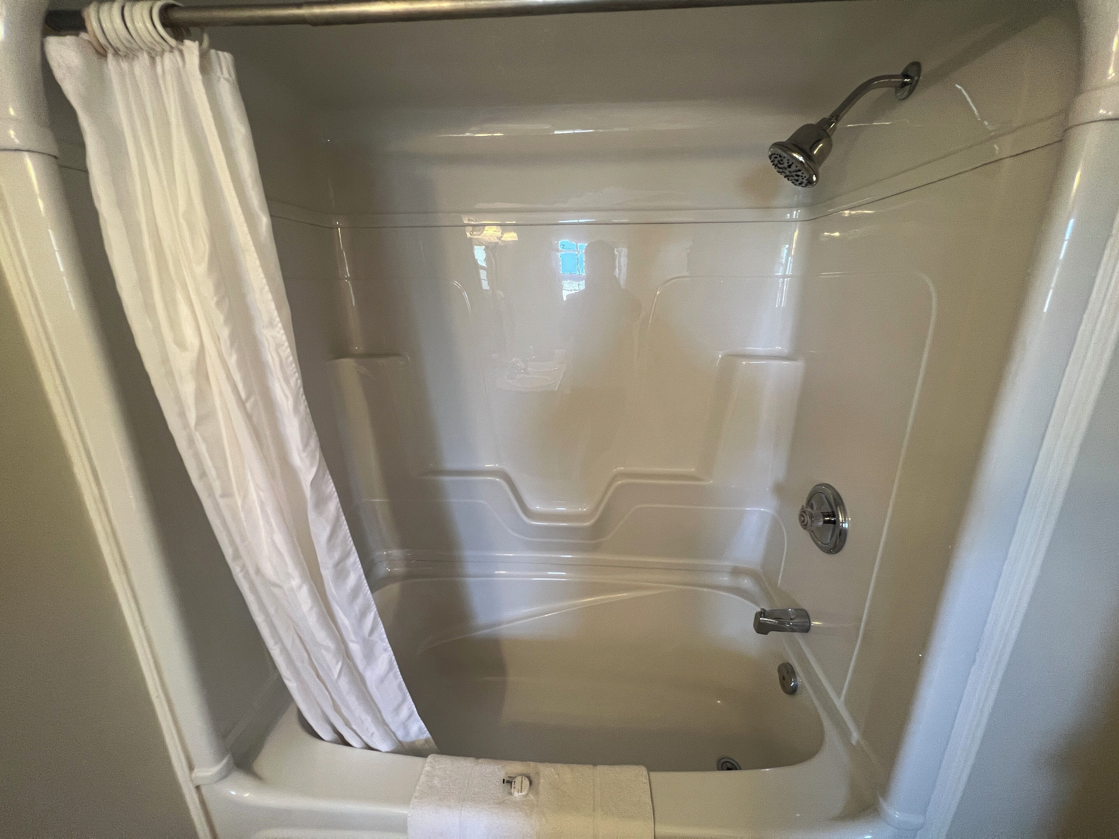 A bathtub with a showerhead and a curtain.