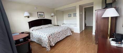 A hotel room with a bed, bedside table, lamp, and a desk with a chair.