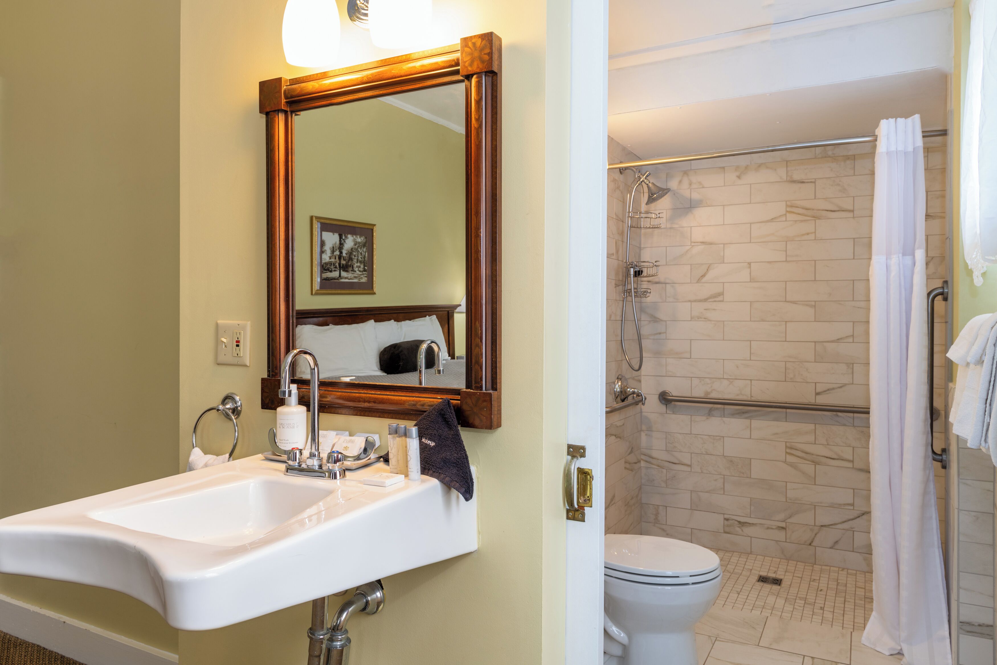 A bathroom with a sink, mirror, and shower area.