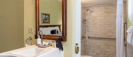 A bathroom with a sink, mirror, and shower area.
